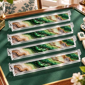 May include: Four rectangular mahjong tile racks made of clear acrylic. Each rack features a decorative insert with a marbled pattern in shades of emerald green, cream, and white, accented with gold-colored glitter veins throughout the design.