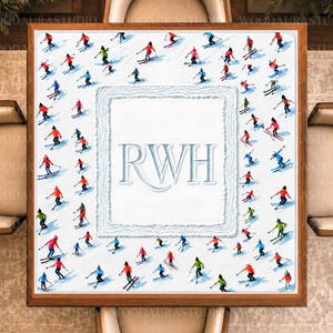 May include: A square wooden-framed wall art piece featuring a white center panel with the embossed letters RWH. The border is decorated with a repeating pattern of small, colorful figures skiing on a white background, creating a winter sports theme.