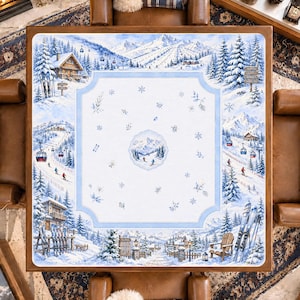 May include: A square tablecloth featuring a detailed winter mountain scene with snow-covered pine trees, ski slopes, cable cars, and wooden chalets. The central panel displays a light blue border with scattered snowflakes and a small circular mountain landscape.