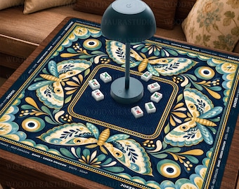 Puede incluir: Un tapete de mahjong cuadrado con fondo azul oscuro y un patrón repetitivo de polillas en color crema y verde azulado, detalles dorados y motivos circulares. Una lámpara verde oscuro en forma de seta se sitúa en el centro con seis fichas.