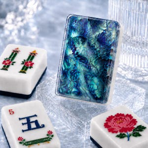 May include: A rectangular mahjong tile featuring a vibrant, iridescent blue and green abalone shell inlay on its front face, surrounded by other white mahjong tiles decorated with red and green floral patterns and the blue Chinese character for five.