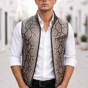 以下が含まれることがあります： 白いシャツと黒いジーンズの上に、黒いジッパーが付いたヘビ柄のベストを着た人。 ベストはハイカラーで、小さなジッパー付きポケットが付いています。 その人はまた、黒いサングラスと黒いベルトを着用しています。