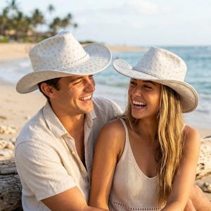 May include: Two off-white cowboy hats featuring a textured, dotted surface pattern and a braided hatband. The hats have a wide, curved brim and a pinched crown design, crafted with a consistent light-coloured finish throughout the entire structure.