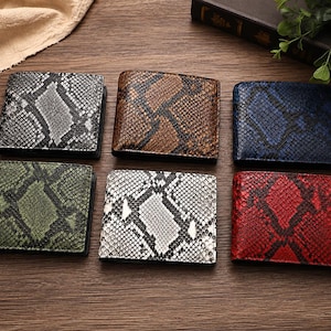 May include: A collection of six bifold wallets featuring a textured snakeskin pattern in various colours including silver, brown, blue, green, white, and red. Each wallet has a rectangular shape with a distinct scale design across the entire surface.