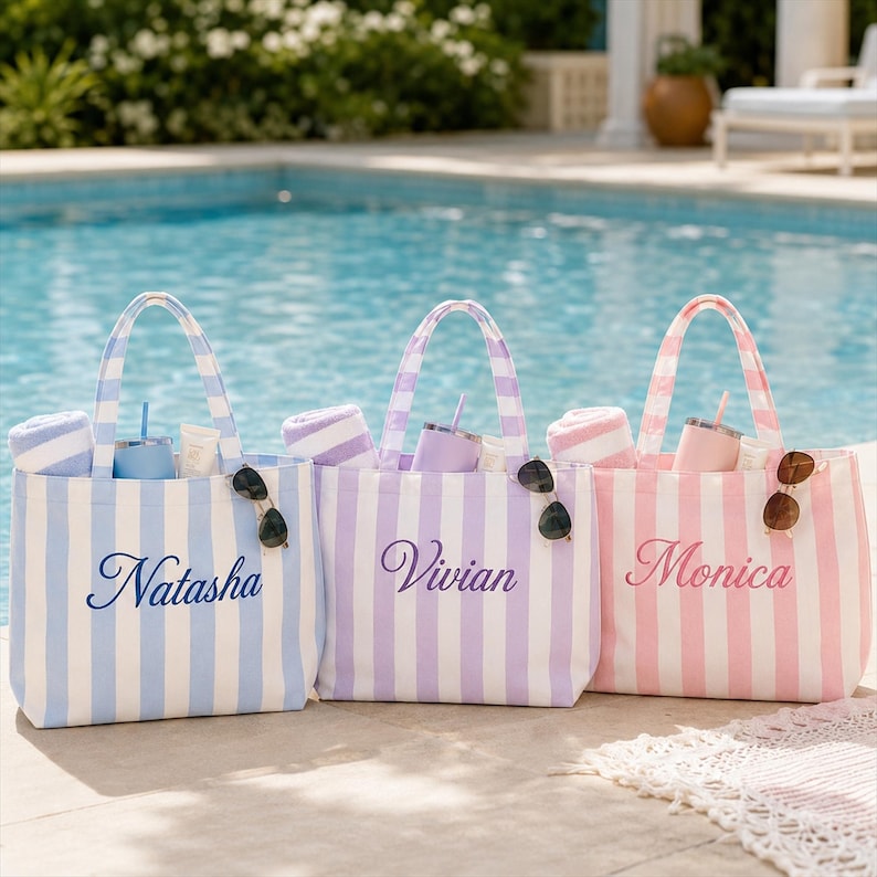 May include: Three striped tote bags in light blue, lavender, and pink, each featuring a name embroidered in cursive script: Natasha, Vivian, and Monica. Each bag contains a matching rolled towel, a tumbler with a straw, and a pair of sunglasses.