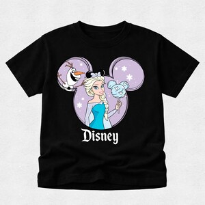 May include: A black short-sleeve t-shirt featuring a graphic of Elsa and Olaf inside a purple Mickey Mouse ear silhouette. Elsa wears black mouse ears and holds a blue Mickey-shaped cotton candy. The word Disney is printed in white below.