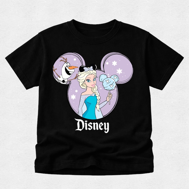May include: A black short-sleeve t-shirt featuring a graphic of Elsa and Olaf inside a purple Mickey Mouse ear silhouette. Elsa wears black mouse ears and holds a blue Mickey-shaped cotton candy. The word Disney is printed in white below.
