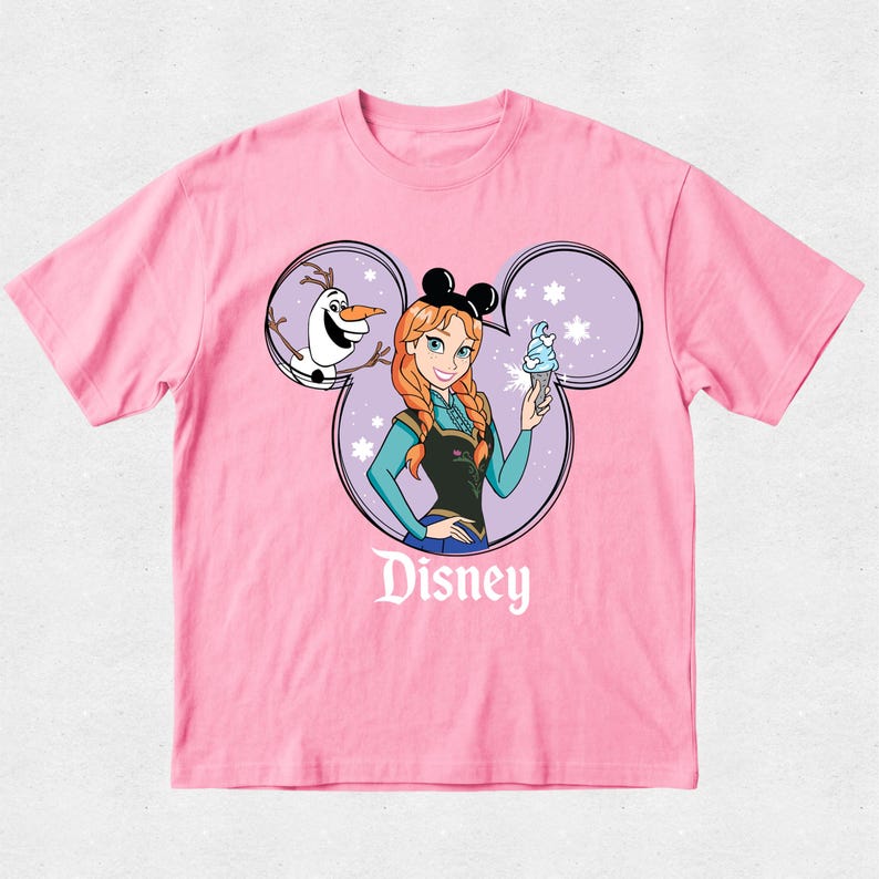 Puede incluir: Una camiseta rosa claro de manga corta con un gr&aacute;fico de Anna de Frozen y Olaf dentro de una silueta de orejas de Mickey Mouse. Anna lleva orejas negras y sostiene un helado azul. La palabra Disney est&aacute; impresa en blanco bajo el gr&aacute;fico.