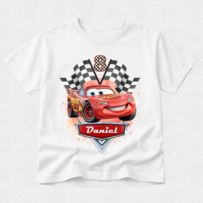 Peut inclure: T-shirt blanc avec une voiture de course rouge de dessin anim&eacute;, le num&eacute;ro 95 et le nom "Daniel" sur un badge. Le motif comprend des drapeaux &agrave; damiers et le chiffre 8, sugg&eacute;rant un th&egrave;me d'anniversaire. La voiture a un visage souriant.
