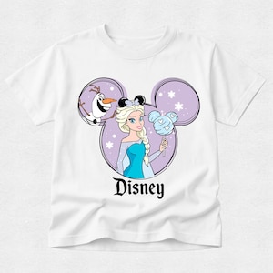 May include: A white short-sleeve t-shirt featuring a graphic of Elsa and Olaf inside a purple Mickey Mouse ear silhouette. Elsa wears black mouse ears and holds a light blue cotton candy treat. The word Disney is printed in black below the graphic.