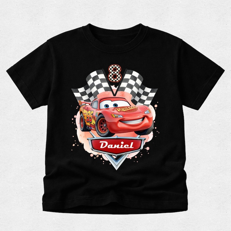Peut inclure: T-shirt noir avec une voiture de course rouge de dessin anim&eacute;, le num&eacute;ro 95, et un drapeau &agrave; damier. Le design comprend le nom "Daniel" sur une banni&egrave;re et le chiffre 8. La voiture a un visage souriant.