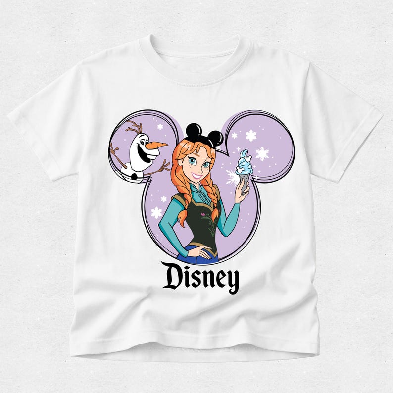 Puede incluir: Una camiseta blanca de manga corta con un gr&aacute;fico de Anna y Olaf dentro de una silueta de orejas de Mickey Mouse moradas. Anna tiene el pelo trenzado, lleva orejas negras y sostiene un helado azul. La palabra Disney aparece impresa en negro.