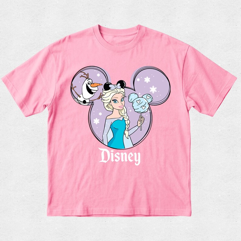 May include: A light pink short-sleeve t-shirt featuring a graphic of Elsa and Olaf inside a purple Mickey Mouse ear silhouette. Elsa holds a blue Mickey-shaped cotton candy treat. The word Disney is printed in white text below the graphic.