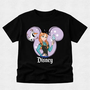 Puede incluir: Una camiseta negra de manga corta con un gr&aacute;fico de Anna de Frozen y Olaf dentro de una silueta de orejas de Mickey Mouse moradas. Anna sostiene un cono de helado azul y la palabra Disney est&aacute; impresa en letras blancas debajo del dise&ntilde;o.