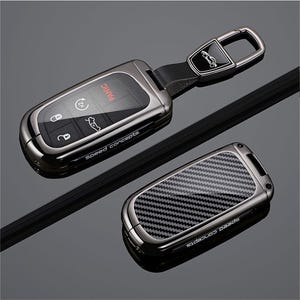 May include: A metallic gunmetal car key fob cover with a black carbon fiber pattern insert. The cover features the text Speed Concepts on the side. One piece includes a matching metallic keychain attachment with a small car icon graphic.
