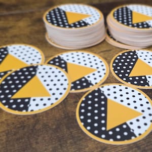 May include: A set of three ceramic mugs with a speckled, cream-colored glaze. Each mug features a different hand-painted design: a blue and green leaf, a yellow flower, and a red berry. The mugs have a simple, rounded shape and a comfortable handle.