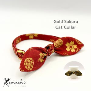 以下が含まれることがあります： 金色の桜模様とリボンが付いた赤い猫用首輪で、金色の金属製バックルが特徴です。Gold Sakura Cat Collarという文字と、Komachi Stitch Studioのロゴ、および小さな挿入画像が表示されています。
