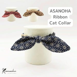 May include: Three cat collars with a fabric ribbon bow featuring the Asanoha geometric star pattern in navy blue, red, and brown. Each collar includes a black plastic buckle and a metal adjuster. The text ASANOHA Ribbon Cat Collar is visible.