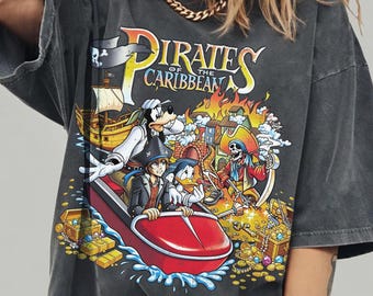 Puede incluir: Una camiseta gris carbón con un estampado gráfico que incluye el texto Pirates of the Caribbean. El diseño muestra personajes de dibujos animados en un bote rojo, un barco pirata y un esqueleto entre tesoros. Incluye Comfort Colors Pepper.