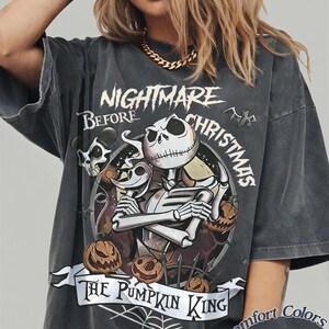 Peut inclure: Un t-shirt gris anthracite oversize avec une illustration de Jack Skellington de L'&Eacute;trange No&euml;l de monsieur Jack et le texte The Pumpkin King. Le motif inclut des citrouilles, une toile d'araign&eacute;e et des chauves-souris. &Eacute;tiquette Comfort Colors Pepper.