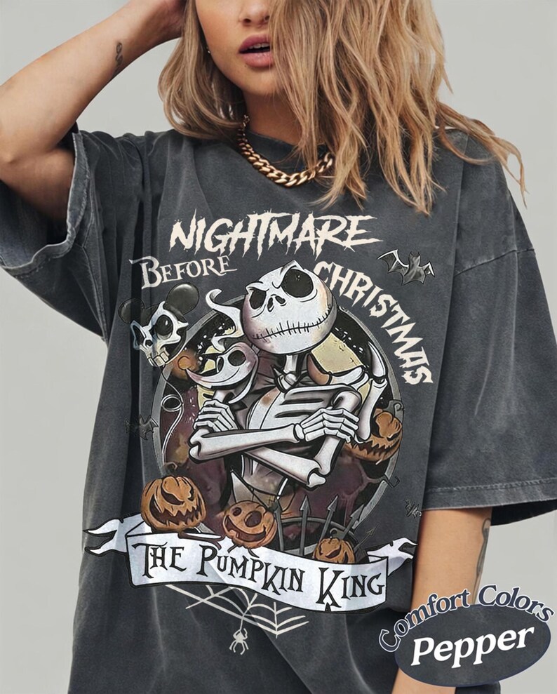 Peut inclure: Un t-shirt gris anthracite oversize avec une illustration de Jack Skellington de L'&Eacute;trange No&euml;l de monsieur Jack et le texte The Pumpkin King. Le motif inclut des citrouilles, une toile d'araign&eacute;e et des chauves-souris. &Eacute;tiquette Comfort Colors Pepper.