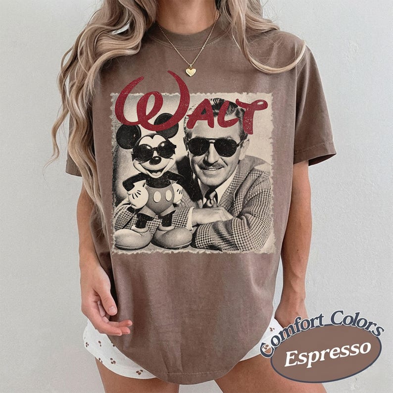 May include: Espresso-colored t-shirt featuring a vintage graphic of Mickey Mouse and Walt Disney. The word "Walt" is in red glitter script above the image. The shirt is a Comfort Colors brand.