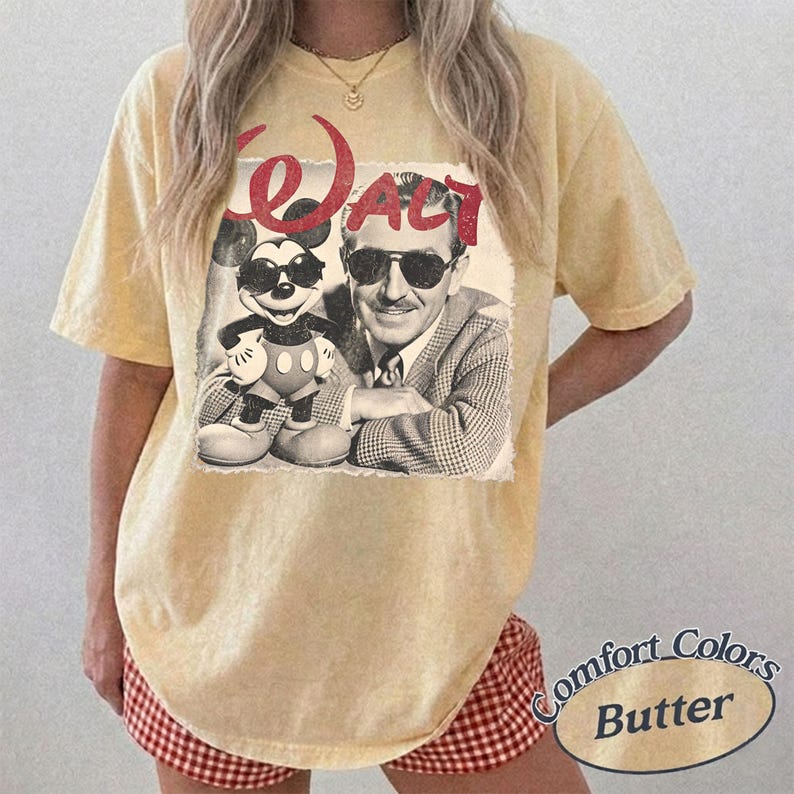 May include: Butter yellow t-shirt featuring a vintage graphic of Mickey Mouse and Walt Disney. The graphic is in black and white with the word "WALT" in red. The shirt is a Comfort Colors brand.