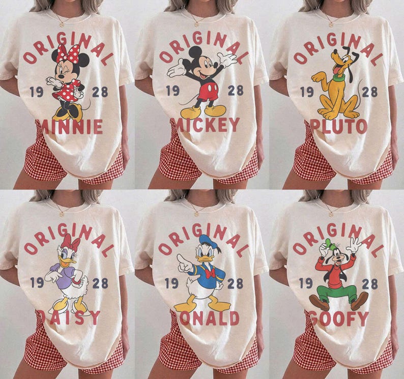 Op de afbeelding: Een collectie van zes cr&egrave;mekleurige T-shirts met Disney-figuren waaronder Minnie Mouse, Mickey Mouse, Pluto, Katrien Duck, Donald Duck en Goofy. Elk shirt toont de tekst ORIGINAL 1928 en de naam van het personage in het rood.
