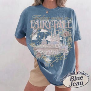 Może przedstawiać: Niebieski t-shirt z kr&oacute;tkim rękawem z nadrukiem graficznym przedstawiającym zamek, motyle i r&oacute;że. Tekst głosi Today was a FAIRY TALE oraz Can you feel this magic in the air? Koszulka ma okrągły dekolt i luźny, swobodny kr&oacute;j.