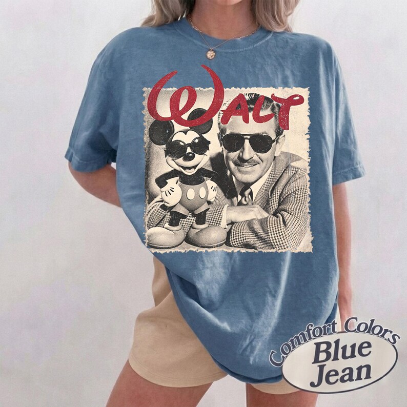 May include: Blue Comfort Colors t-shirt featuring a vintage graphic of Mickey Mouse and Walt Disney in sunglasses. The word "Walt" is in red script above the image. The shirt is labeled "Blue Jean".