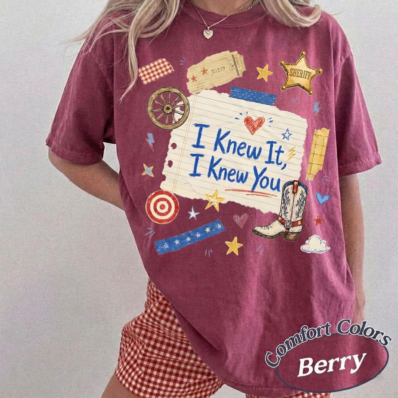 Puede incluir: Una camiseta de manga corta color baya con un estampado gr&aacute;fico de una p&aacute;gina de cuaderno rayada con el texto azul I Knew It, I Knew You. El dise&ntilde;o incluye una bota de vaquero, una estrella de sheriff, una rueda de carro y estrellas y corazones.