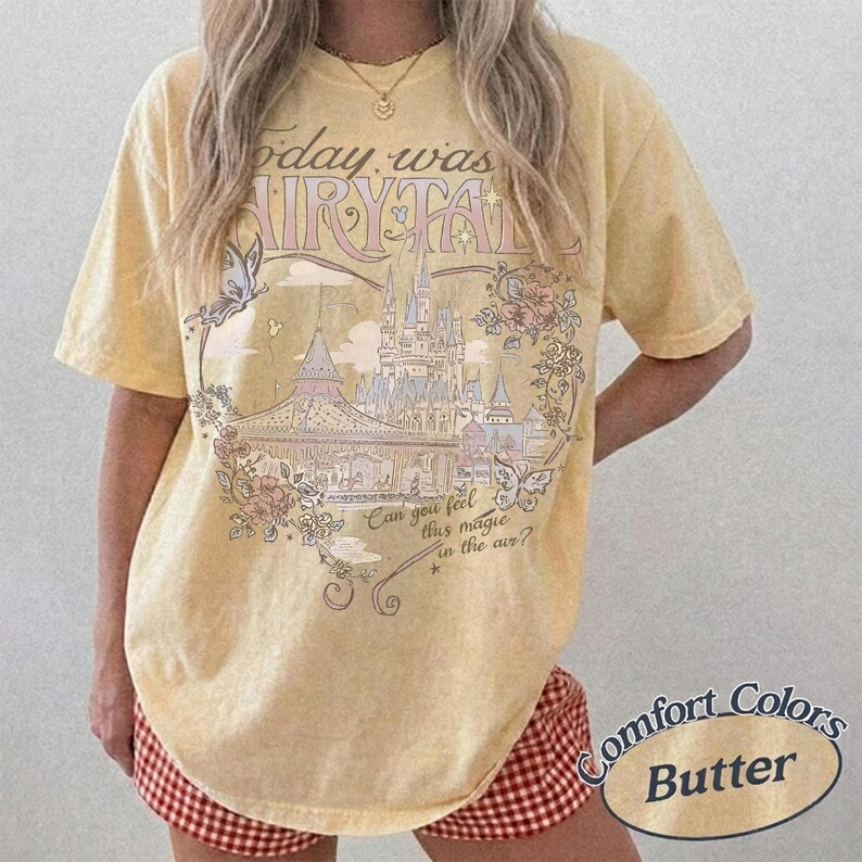 Może przedstawiać: Bladoz&oacute;łty t-shirt z kr&oacute;tkim rękawem z nadrukiem przedstawiającym zamek, motyle i kwiaty. Tekst głosi: Today was a fairytale. Can you feel this magic in the air? Koszulka ma okrągły dekolt i luźny kr&oacute;j, zapewniający swobodę ruch&oacute;w.