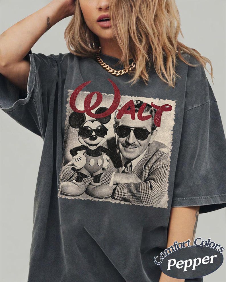 May include: Dark grey t-shirt featuring a black and white image of Mickey Mouse and Walt Disney wearing sunglasses. The word "WALT" is printed in red above the image. The shirt is from Comfort Colors.