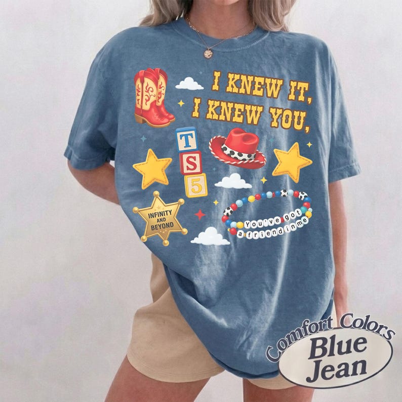 Pode incluir: Uma t-shirt azul de manga curta com uma estampa gr&aacute;fica com o texto I KNEW IT, I KNEW YOU, uma bota de cowboy vermelha, um chap&eacute;u de cowboy vermelho, estrelas amarelas, blocos empilhados TS 5, uma estrela com INFINITY AND BEYOND e uma pulseira.