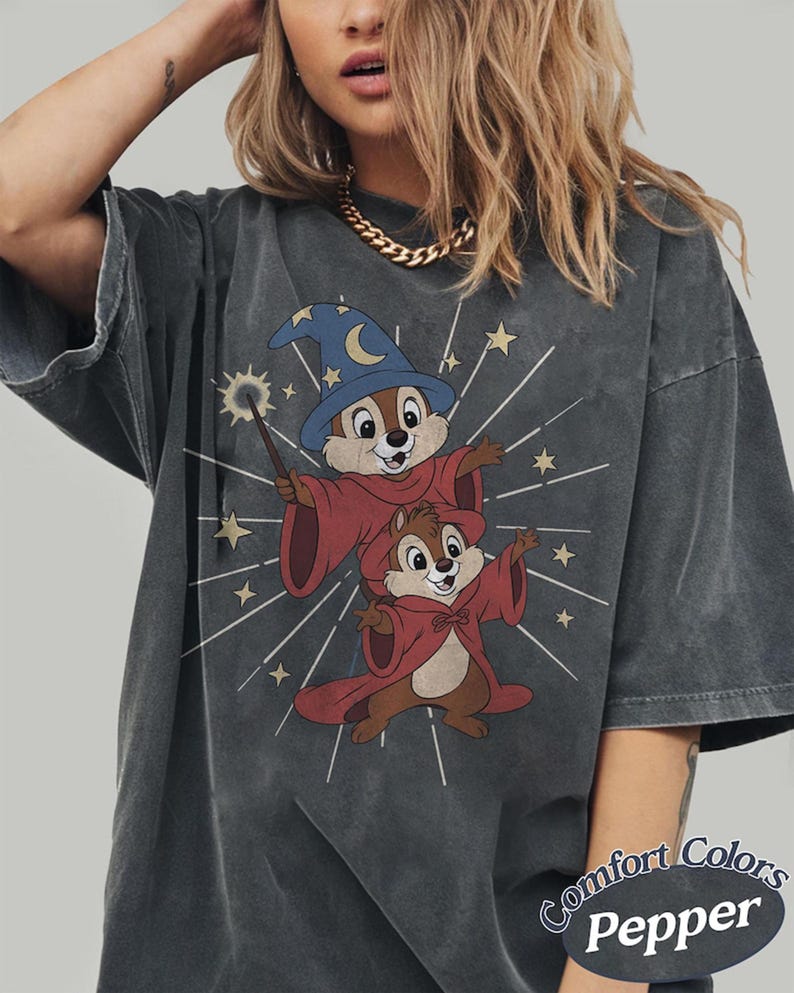 Op de afbeelding: Donkergrijs t-shirt met een cartoon illustratie van twee chipmunks verkleed als tovenaars, een met een toverstaf. De chipmunks dragen rode gewaden en blauwe tovenaars hoeden. De tekst "Comfort Colors Pepper" staat rechtsonder.