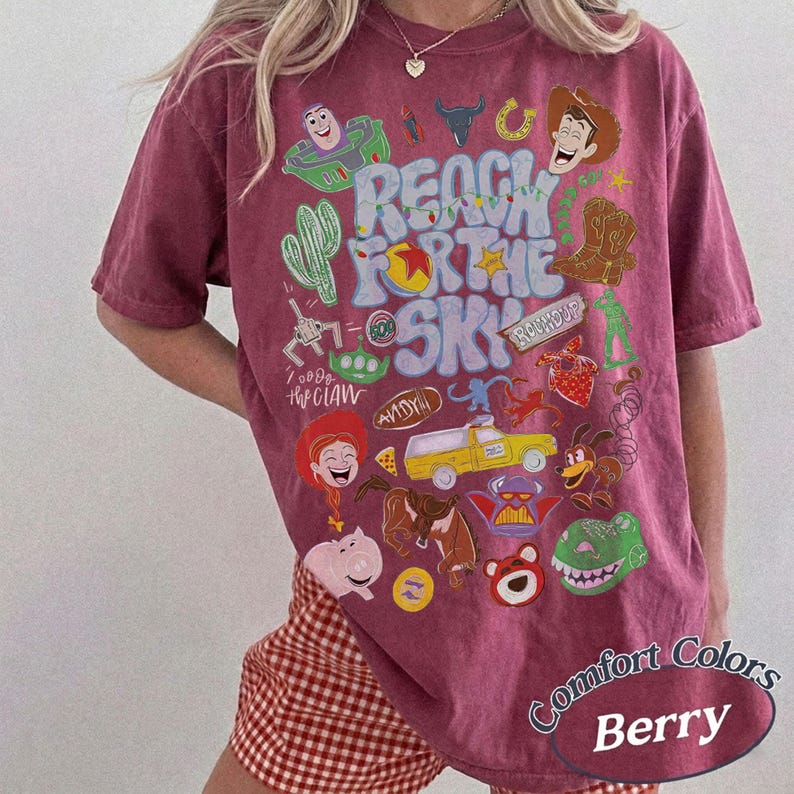Peut inclure: Un t-shirt &agrave; manches courtes de couleur baie avec une impression graphique portant le texte REACH FOR THE SKY. Le motif comprend divers personnages de dessins anim&eacute;s, un camion jaune, un cactus, un chapeau de cow-boy et un cochon.
