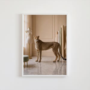 Peut inclure: Impression encadrée d'un guépard dans une pièce avec un mannequin, des rouleaux de tissu et un tabouret. Le guépard a un pelage beige avec des taches noires. La pièce a une palette de couleurs neutres avec un sol en marbre.