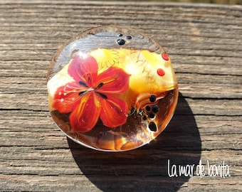 la mar de bonita - lampwork medaillon focal bead with poppy on a cream colored background