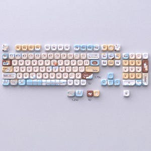 May include: A custom keyboard with keycaps in various colours, including beige, blue, and brown. The keycaps feature unique designs and text, with a layout that includes function keys, alphanumeric keys, and a number pad. The keyboard is designed for a personalized aesthetic.