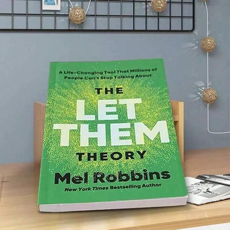 May include: A hardcover book titled "THE LET THEM THEORY" by Mel Robbins. The book has a green cover with white text. The cover also includes the text "A Life-Changing Tool That Millions of People Can't Stop Talking About" and "New York Times Bestselling Author".