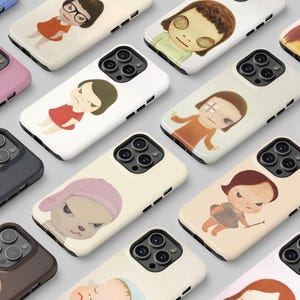 May include: A collection of smartphone cases featuring various stylized illustrations of characters with large eyes and expressive faces. Each case displays a unique portrait or figure in different colors, including pink, white, black, and beige, with camera cutouts.