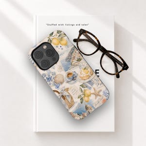 May include: A smartphone case featuring a collage of Amalfi Coast imagery, including yellow lemons, a cup of espresso, a seashell, a starfish, and coastal architecture. The case has a black camera cutout and is paired with dark brown tortoiseshell glasses.