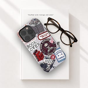 May include: A phone case with book-themed stickers, including a skull and the words "Book Lover." The case is on a white book next to tortoiseshell glasses. The text "Reading is my therapy" is visible. The case is grey.