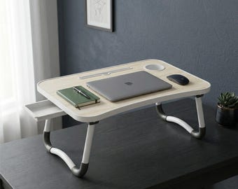 Mesa portátil plegable blanca con puertos USB y almacenamiento.