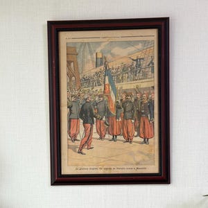 Peut inclure: Une collection d'objets décoratifs sur un meuble en bois foncé. Comprend une impression encadrée, des statues en bois d'un Bouddha, une figurine faisant le poirier et deux autres figurines. Une plante en pot et une bougie rouge dans un verre sont également présentes.