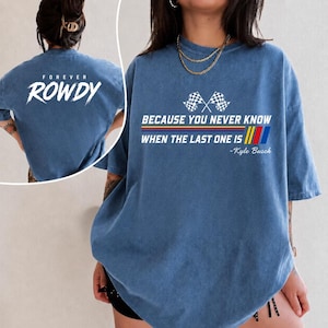 May include: Blue t-shirt with the text "FOREVER ROWDY" on the back and "BECAUSE YOU NEVER KNOW WHEN THE LAST ONE IS" with checkered flags and stripes on the front. The shirt also includes the name "-Kyle Busch".