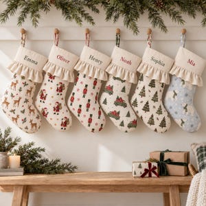 Op de afbeelding: Zes hangende kerstsokken met ruches, elk gepersonaliseerd met de namen Emma, Oliver, Henry, Noah, Sophia en Mia. De sokken hebben feestelijke patronen met herten, de Kerstman, notenkrakers, vrachtwagens, dennenbomen en ijsberen.