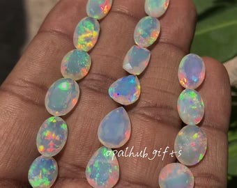 May include: A collection of opals in various shapes, including oval and teardrop. The opals display a play of color with flashes of red, green, and blue. The text "opalhub gifts" is visible.