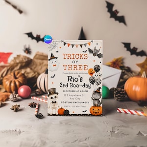 May include: A rectangular Halloween party invitation card featuring the text TRICKS OR THREE, Rio's 3rd Boo-day, 31 OCTOBER AT 6:00PM, 125 Anywhere St., Any City, COSTUME ENCOURAGED, and RSVP: 123-456-7890, decorated with a ghost, skeleton, cat, and pumpkins.