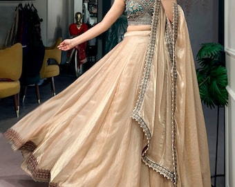 Lehenga Choli de seda com estampa Rangoli em tons de champanhe dourado e blusa verde-azulada.
